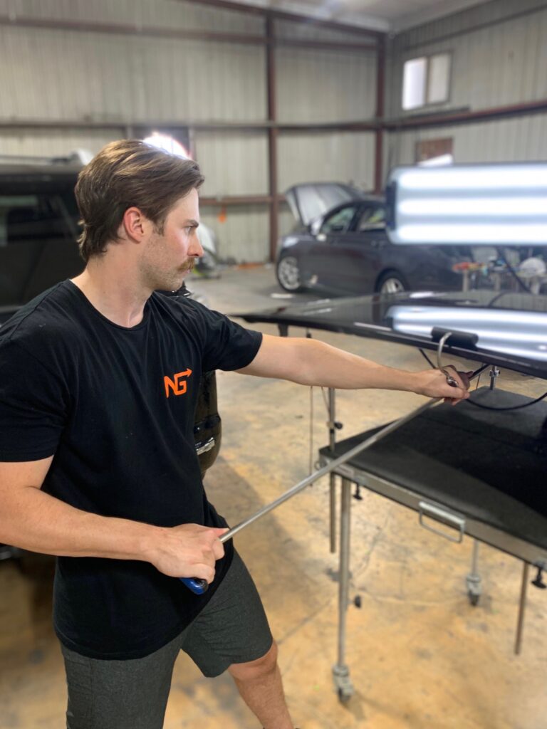 Next Gen's owner working the hail dents out of a panel using PDR techniques